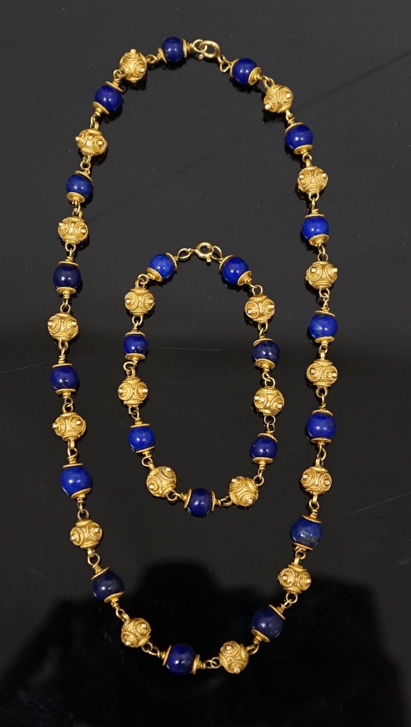 A 20th century Middle Eastern high carat gold canetile work bead and lapis lazuli bead set necklace and matching bracelet